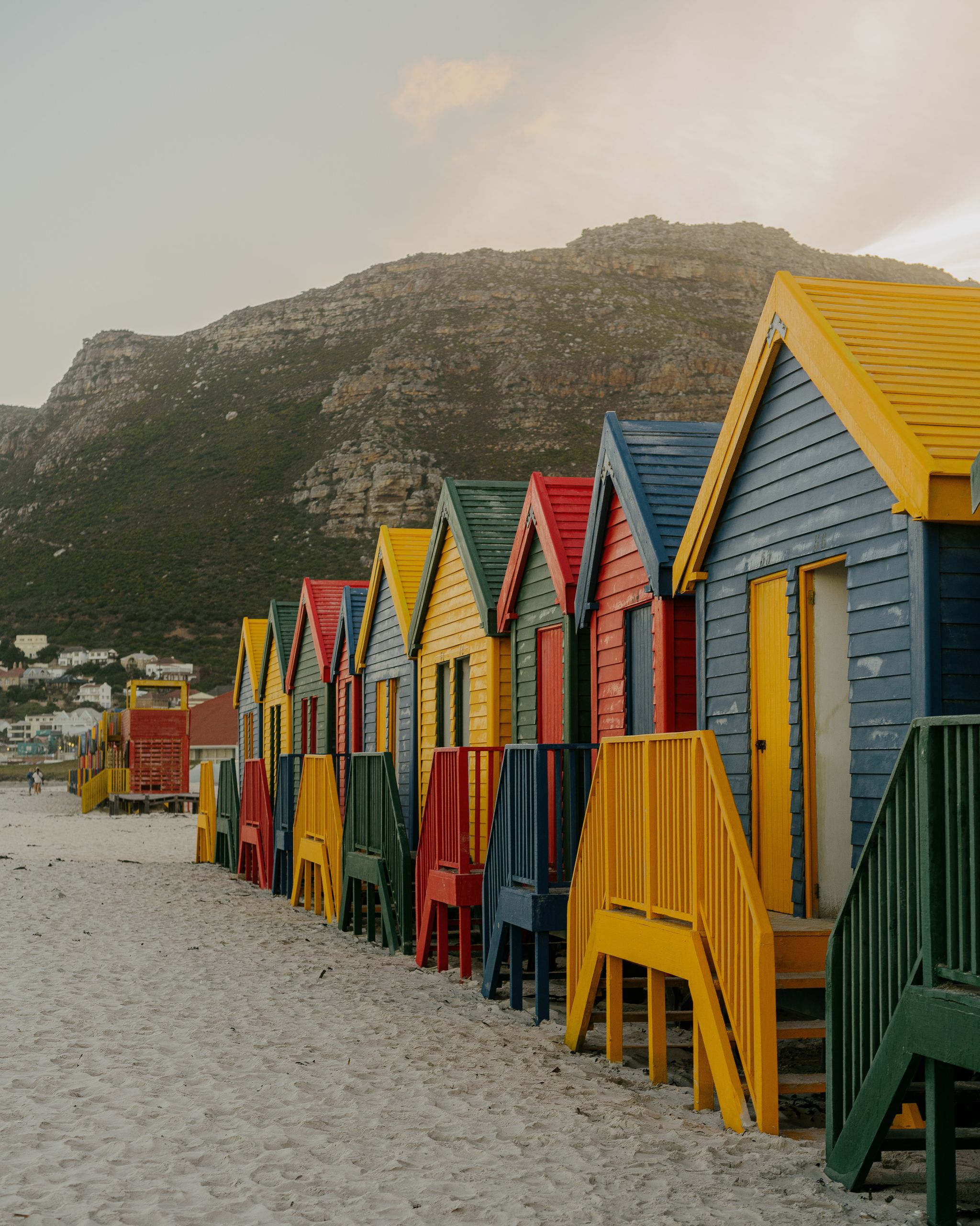Vibrant beach huts line the sandy shore at Muizenberg, Western Cape, South Africa.